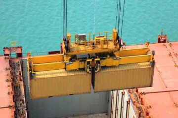 a crane is putting cargo container in ship